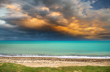 Landscape of the sea coast before the approach of a strong storm. Algae on the beach and choppy waves on the water.