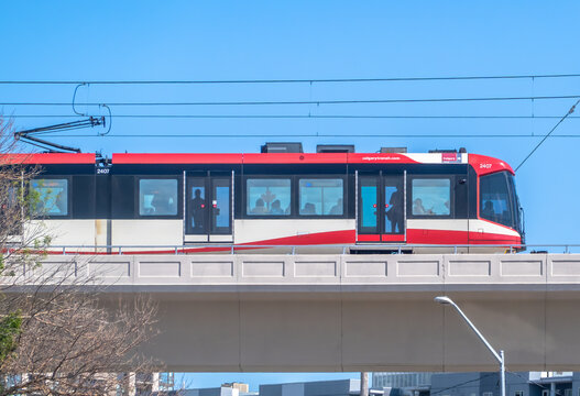 Calgary, Alberta, Canada. Jul 04, 2024. A C-Train in Calgary traveling across a concrete bridge on a clear, blue-sky day.