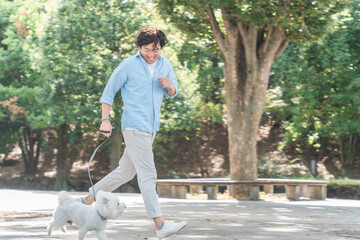 Obraz premium 公園で犬の散歩をする中年・ミドルの日本人男性（走る） 
