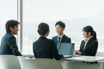 企業のオフィスで笑顔で会議・ミーティング・商談をするアジア人ビジネスマンとビジネスウーマン  © buritora