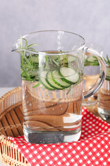 Refreshing cucumber water with rosemary in jug on table
