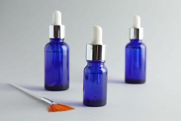 Bottles of chemical peel and brush on light background, closeup. Peeling procedure