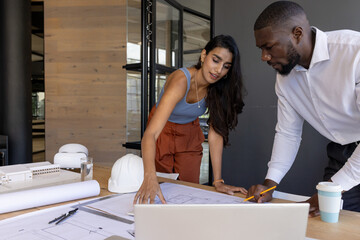 Architects discussing blueprints and planning project, working together in office