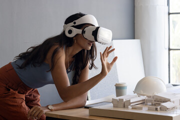 Using VR headset, woman interacting with architectural model in office, copy space