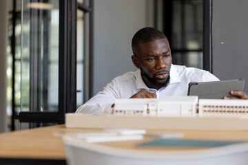 Architect working with tablet and model building in modern office