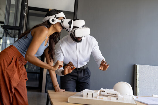 Using VR headsets, colleagues exploring architectural model in modern office