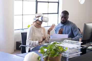 Using VR headset, business colleagues discussing project at office desk