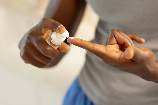 Applying lotion, man using skincare product for self-care at home