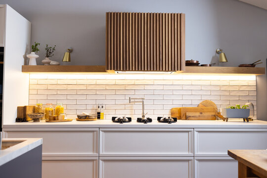 Modern kitchen with wooden accents and white cabinets, featuring gas stovetop, copy space