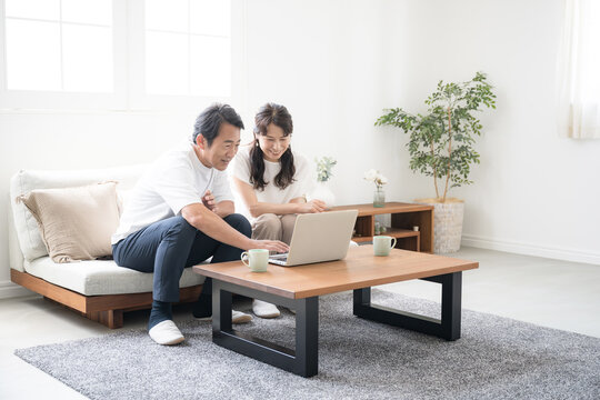 A couple in their 50s discussing over a computer in a bright and clean living room Image wide angle looking for real estate and travel　