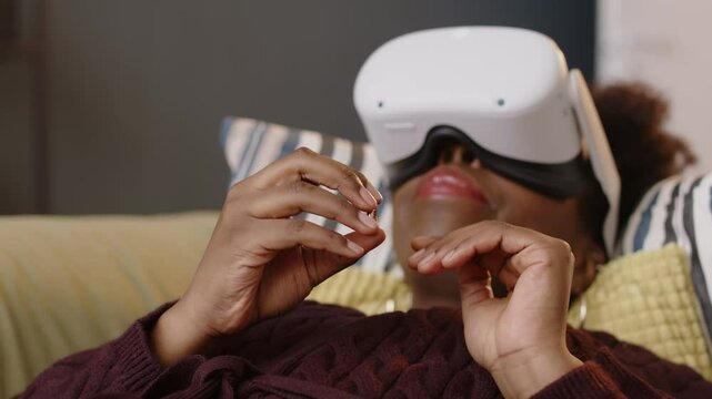 Young Black woman lying on couch at psychologist office wearing VR glasses, taking off wedding ring from her finger, touching, putting it on again and sharing her feelings