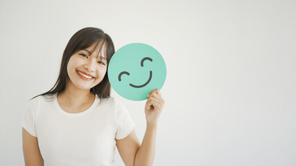 Happy young Asian woman holding smile emoji face, positive mental health, world mental health day...