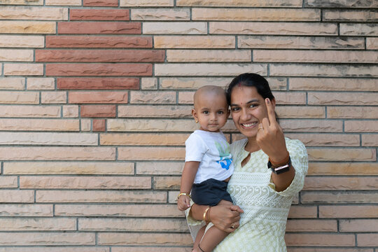 Picture of an Indian woman along with her baby showing her finger after casting vote in election. Lok sabha, vidhan sabha, polls, election commission of india, technology, democarcy, voice, choice