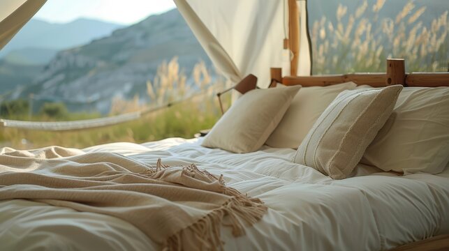 Cozy outdoor glamping bed with pillows and blankets overlooking scenic mountain landscape, perfect for serene getaways and nature retreats.