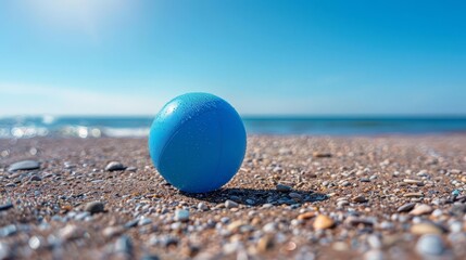 A minimalist image of a blue beach ball on a sunny, sandy beach