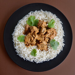 A top view og lamb korma with basmati rice and coriander leaves.