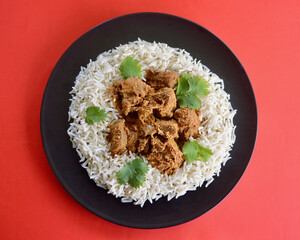 A top view og lamb korma with basmati rice and coriander leaves.