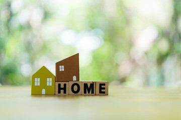 Home model placed on wood block of HOME against natural background with copy space