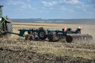 the tractor processes the field with a disc harrow after harvesting. agricultural work in the field...