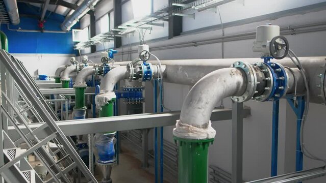 Metal pipe with flange linked to plastic tubes at chemical plant. Refinery factory has water distribution pipeline installed with heavy machinery