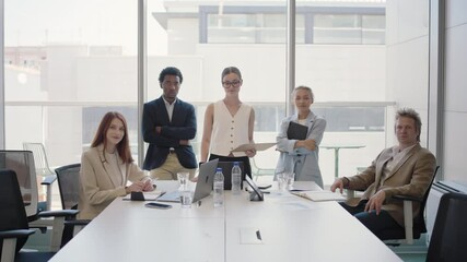 A diverse team of young business professionals are gathered in a modern office meeting room, displaying teamwork and collaboration. The group looks confident and ready for a productive session.