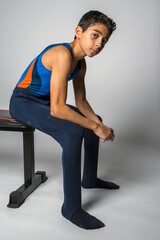 Obraz premium Male youth gymnast sitting on a bench, getting into a competitive mindset before performing an event
