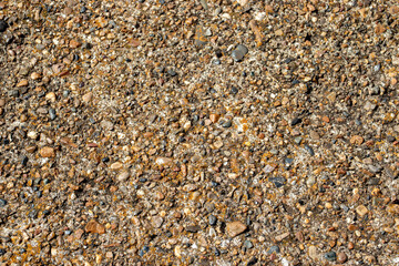 Large and small pebbles on the surface of concrete, top view. Various-sized pebbles, flat layout. Pebbles of different sizes lie chaotically.