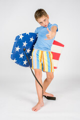 Cute beach boy surfer posing with his boogie board while flashing the hang loose hand gesture with...
