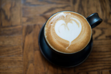 Hot cappuccino coffee with milk latte art of heart shape on wood