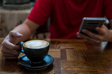 Male customer use cellphone near Hot Latte art coffee