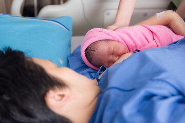 Cute newborn baby girl on nurse hands feed breastmilk by mom