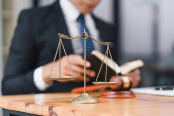 Scales of Justice on a table with a lawyer in the background, symbolizing legal balance and the justice system.