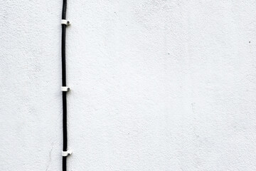 Cable with White Plastic Clips on Concrete Wall Background.