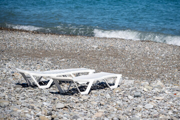 Empty white plastic sun loungers on the sea beach.