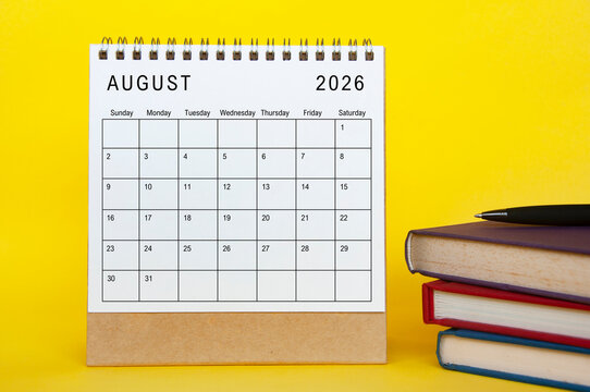 August 2026 calendar with yellow cover background and books. New month and calendar concept
