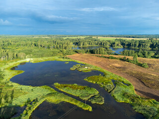 A beautiful aerial panorama of a small lake between green summer trees and fields. Natural...