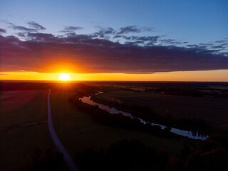 A beautiful river flowing through the Latvia countryside during summer sunrise. Natural morning scenery from the air.