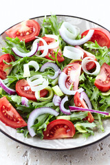Salad with fresh tomatoes and arugula on a bright background. Close up.