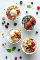 Four bowls filled with delicious desserts containing yogurt, berries and nuts on white background