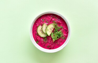Cold summer beetroot soup in bowl over green background