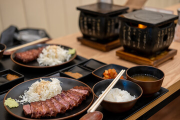 Set of Gyukatsu or beef cutlet served with cabbage. A traditional Japanese food that consists of a deep-fried beef cutlet. With the stone grill on the background