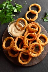 Heap of deep fried onion rings on wooden serving dish