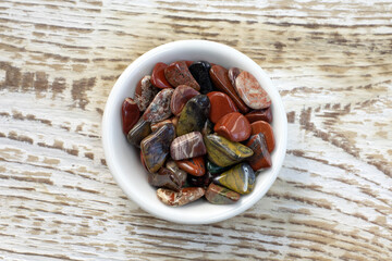 Red and multicolored jasper polished tumblestones as nice natural background on white plate