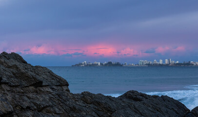 Pink clouds in a gray sky at sunset over Coolangatta, part of the Gold Coast in Queensland, Australia, as seen across the bay from The Rock at Currumbin.