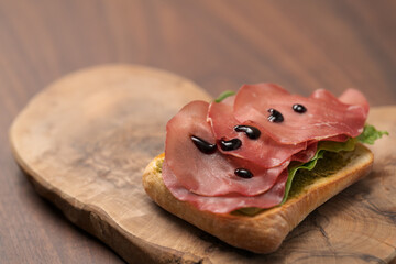 Sandwich with bresaola, pesto and balsamic on olive board
