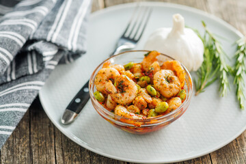 Fresh salad with shrimps and edamame soybeans in bowl on wooden table.