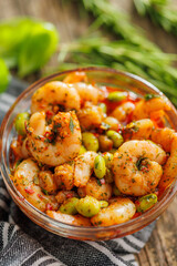 Fresh salad with shrimps and edamame soybeans in bowl on wooden table.