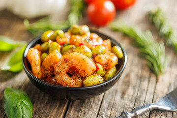 Fresh salad with shrimps and edamame soybeans in bowl on wooden table.