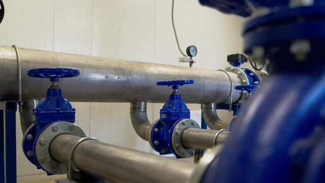 Pressure control round lever on metal pipeline at plant. Product distribution pipe system at factory demonstrating industrial equipment