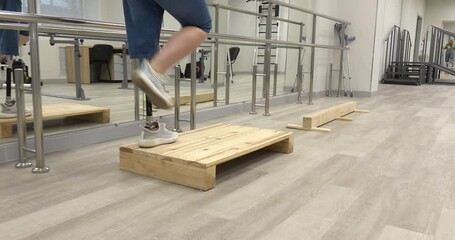 A woman with a modern robotic prosthetic leg is working out in the gym. Physiotherapy rehabilitation that allows a disabled person to walk again. - Powered by Adobe